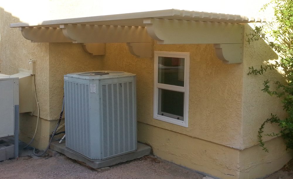 Outdoor residential air conditioning unit installed beside a home with protective shade cover in Largo, FL